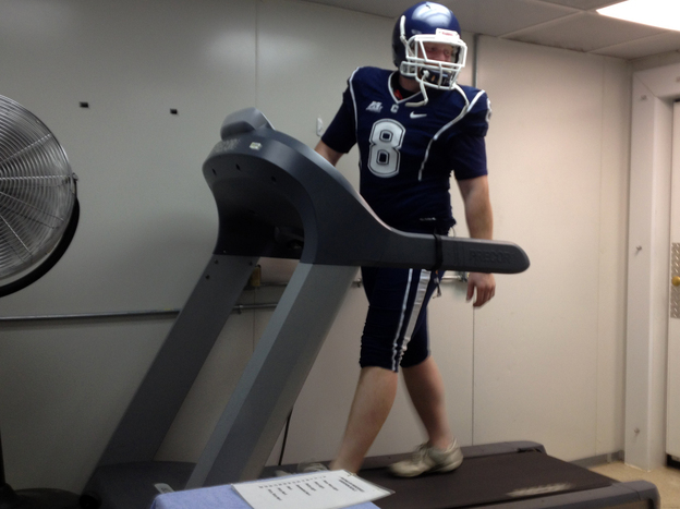 Doctoral student Brett Comstock wears a football uniform as he walks on a treadmill at the Korey Stringer Institute at the University of Connecticut.