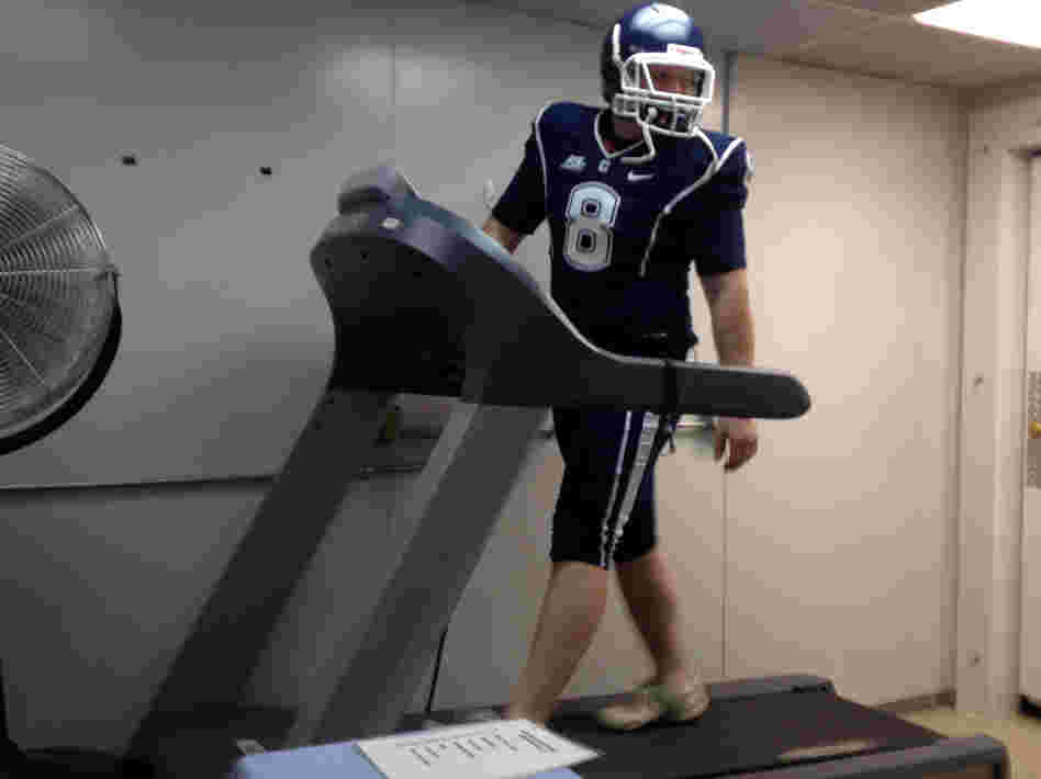 Doctoral student Brett Comstock wears a football uniform as he walks on a treadmill at the Korey Stringer Institute at the University of Connecticut.