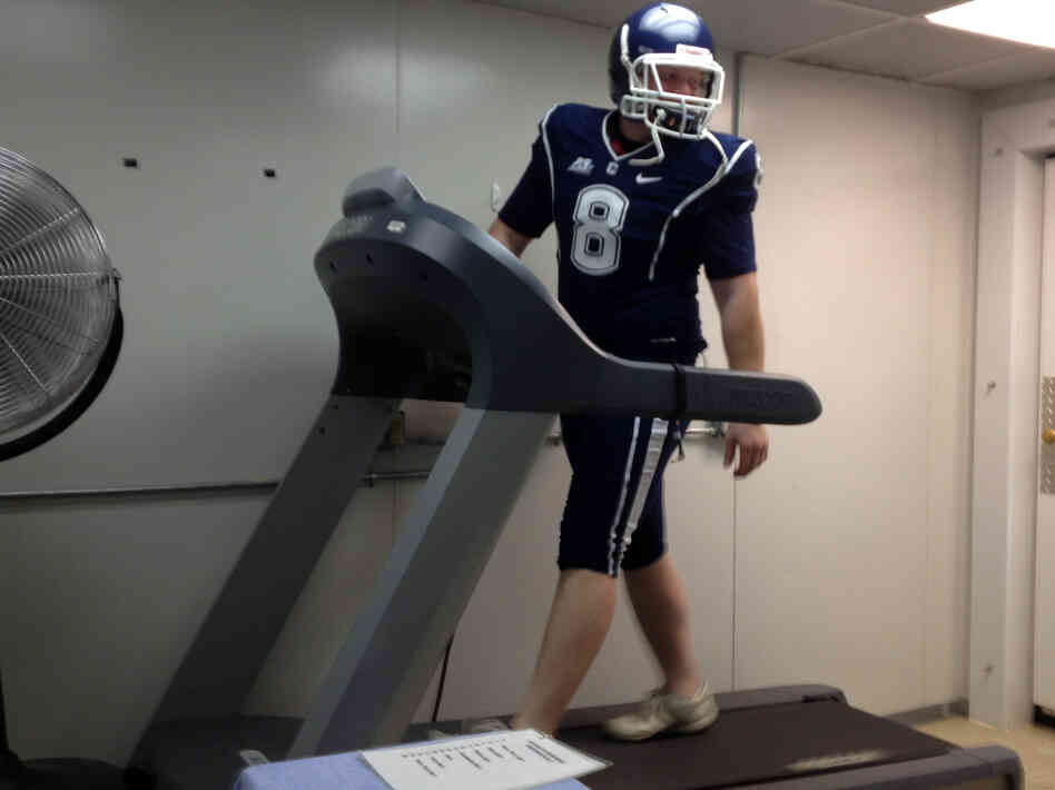 Doctoral student Brett Comstock wears a football uniform as he walks on a treadmill at the Korey Stringer Institute at the University of Connecticut.