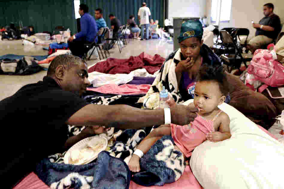 Gus Williams feeds his step-granddaughter, Somaya Washington, as her mother, Areonisha Washington, watches. They evacuated to a shelter in Houma, La.