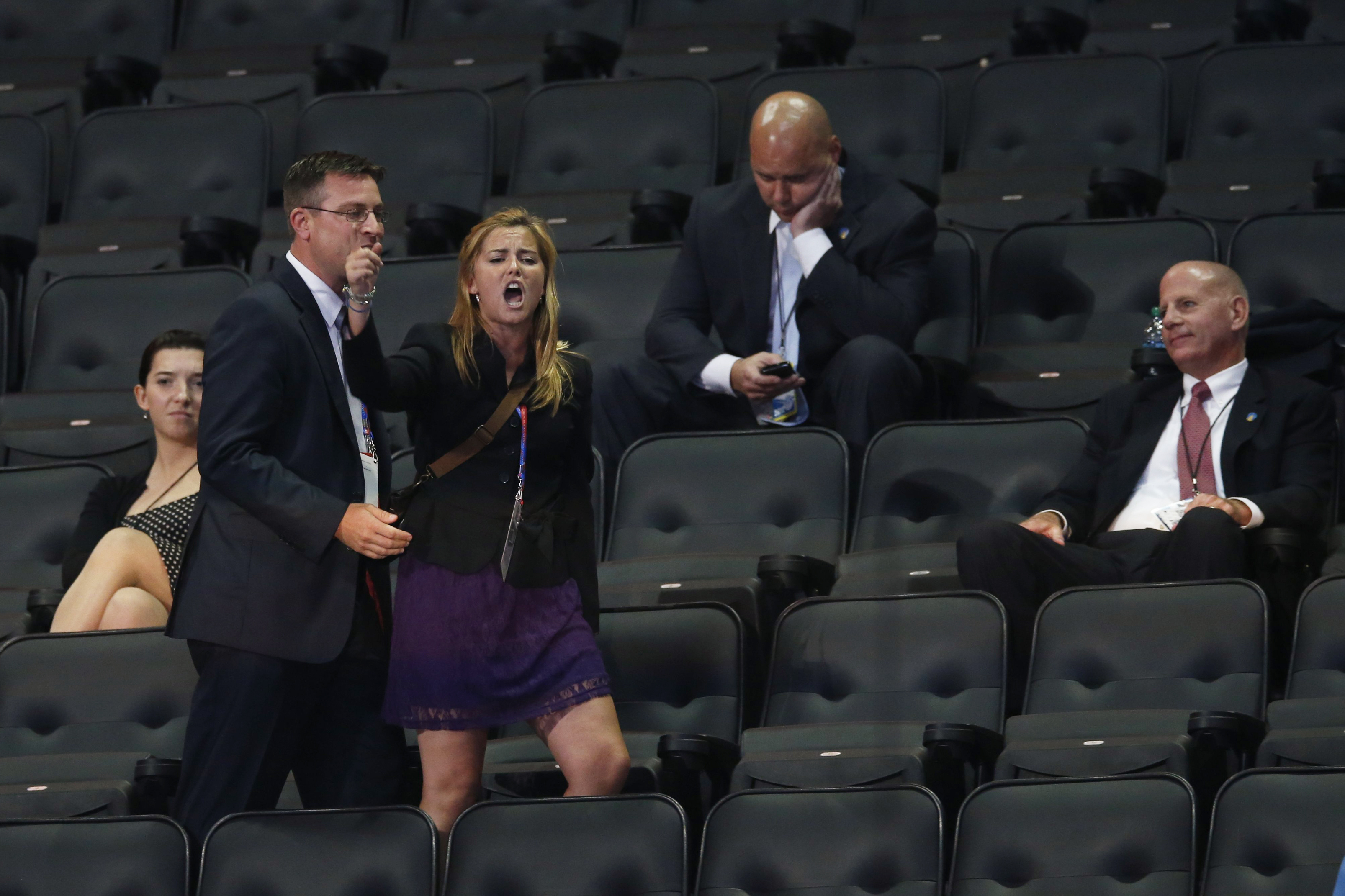 A demonstrator shouting "Stop the War on Women" screams during Rick Santorum's speech before being escorted out of the arena by security.