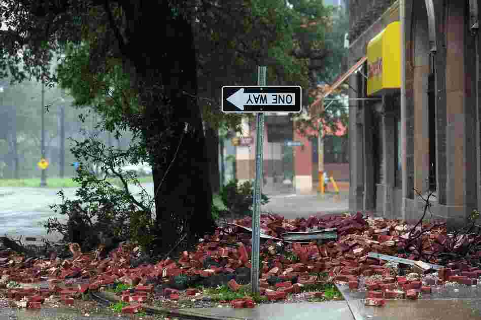 A street sign is turned upside down and bricks cover the sidewalk of a deserted street in New Orleans.