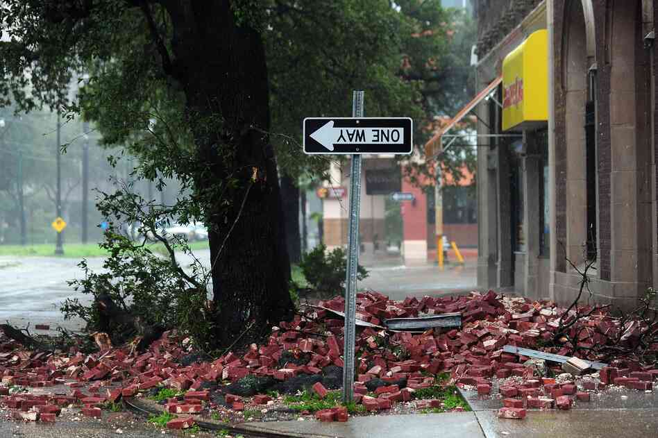 A street sign is turned upside down and bricks cover the sidewalk of a deserted street in New Orleans.