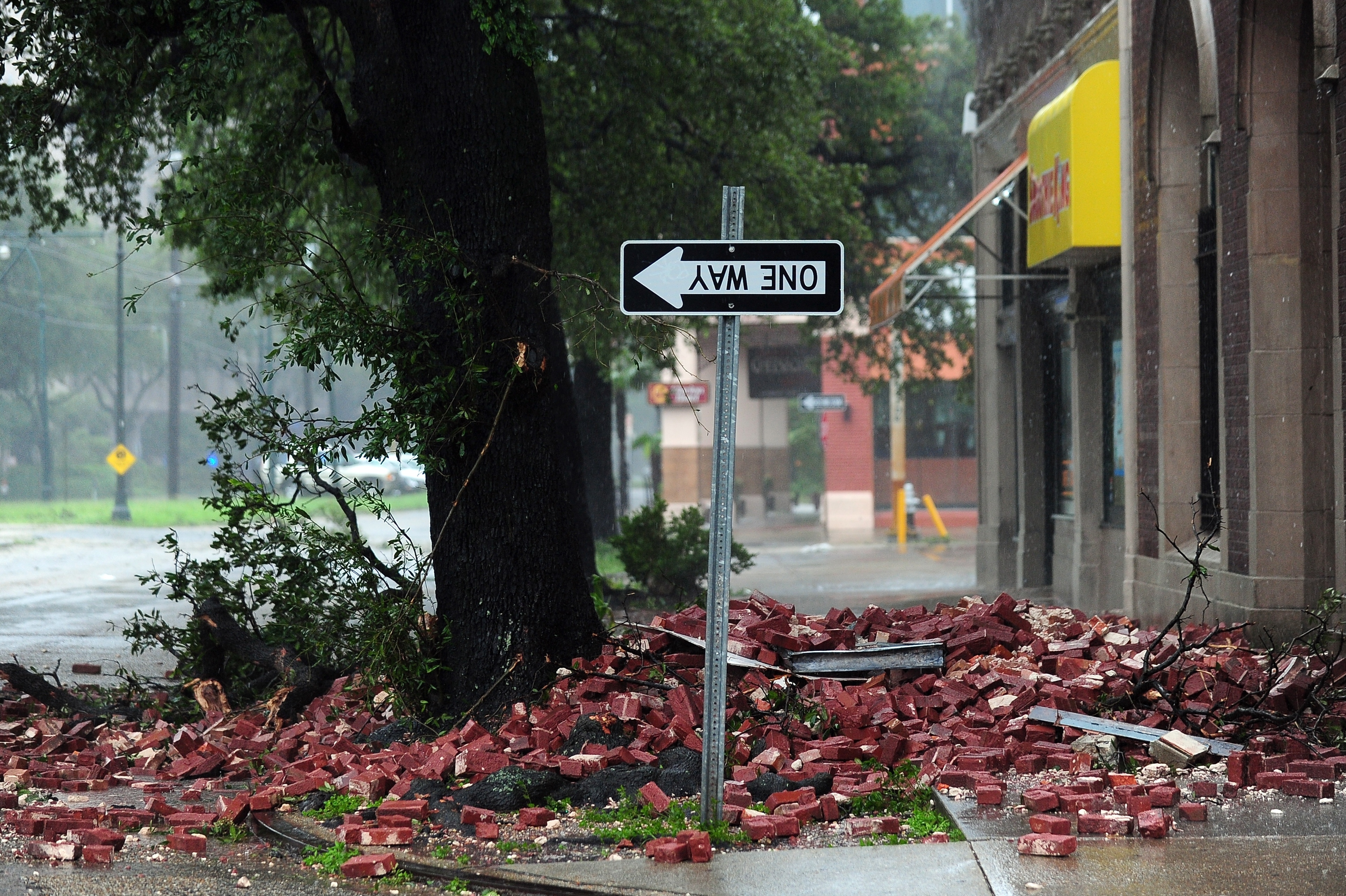 A street sign is turned upside down and bricks cover the sidewalk of a deserted street in New Orleans.