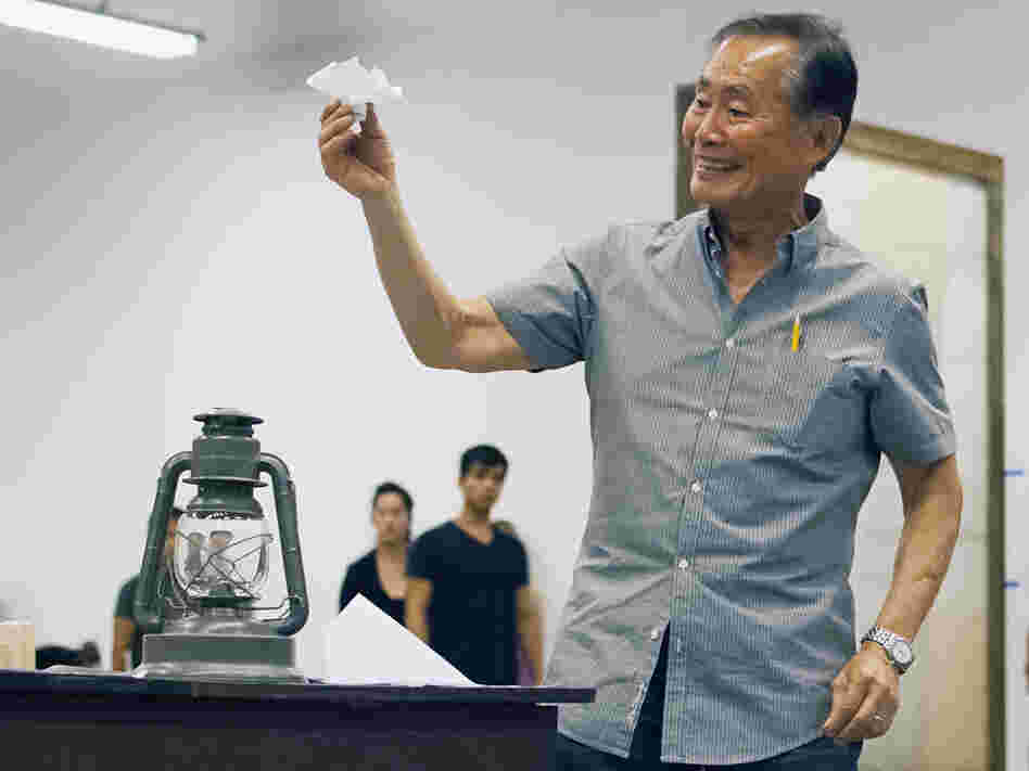 Takei rehearses a scene in which his character, Ojii-San, tries to cheer his granddaughter up by making her an origami flower out of a loyalty questionnaire.