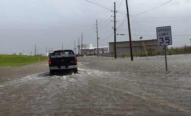 A Plaquemines Parish vehicle rides through rising floodwater behind the levee as Isaac approaches on Tuesday.