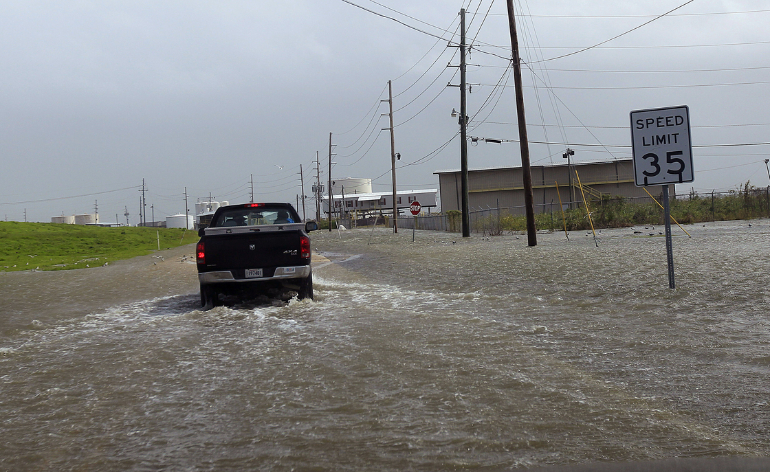 A Plaquemines Parish vehicle rides through rising floodwater behind the levee as Isaac approaches on Tuesday.