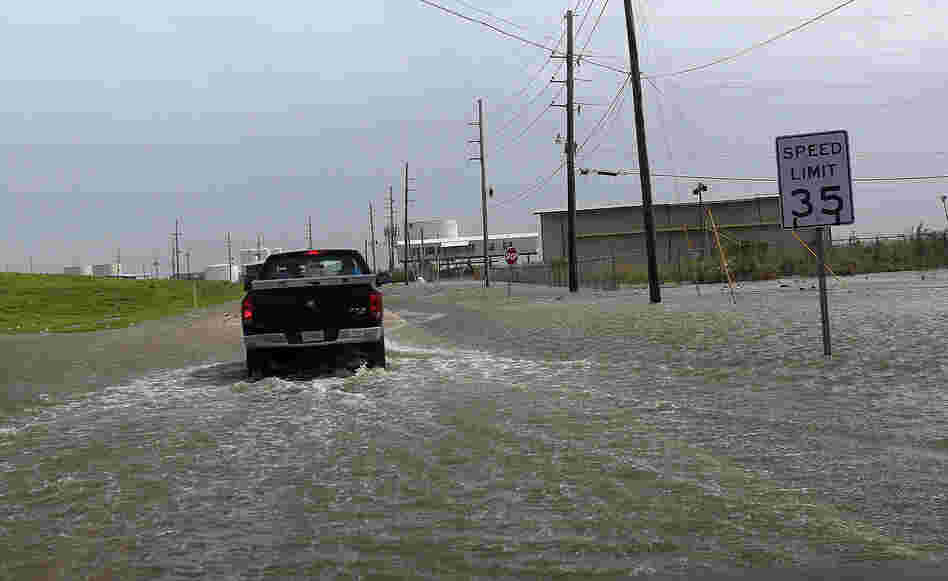 A Plaquemines Parish vehicle rides through rising floodwater behind the levee as Isaac approaches on Tuesday.