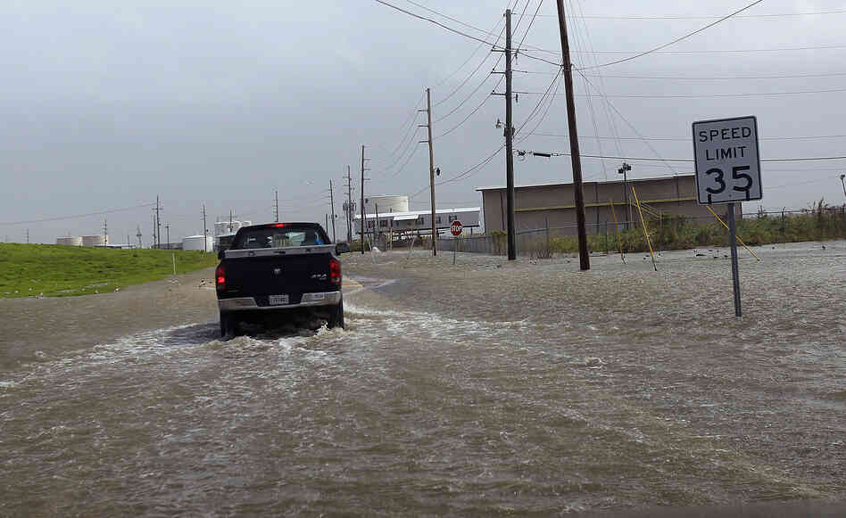 A Plaquemines Parish vehicle rides through rising floodwater behind the levee as Isaac approaches on Tuesday.