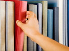 Image of a hand selecting a red book from a bookshelf Image of a hand selecting a red book from a bookshelf