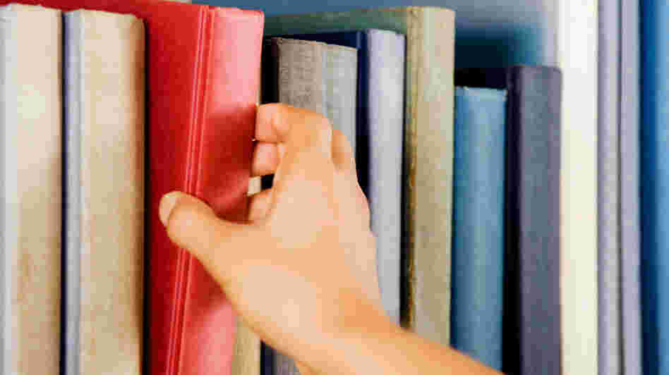 Image of a hand selecting a red book from a bookshelf