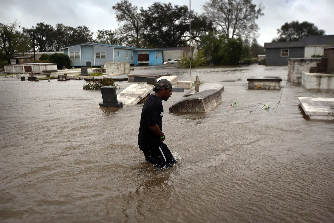 Errol Ragas walks past a cemetery to recover dry blankets from his home as rising waters from Hurricane Isaac flood the neighborhood  of Oakville in Plaquemines Parish, Louisiana.