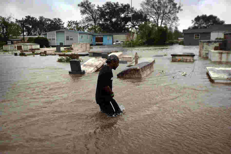 Errol Ragas walks past a cemetery to recover dry blankets from his home as rising waters from Hurricane Isaac flood the neighborhood  of Oakville in Plaquemines Parish, Louisiana.