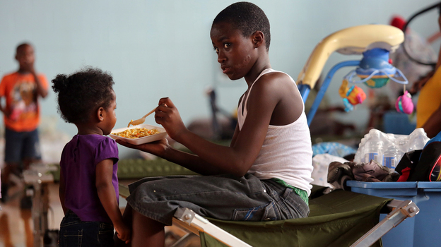 Darrell Hill, 11, feeds his sister Floy Dillon, 2, at a flood shelter in a school gym in Kentwood, La., Thursday. Residents fled to the shelter after officials announced that a dam upstream in Mississippi was in danger of bursting.