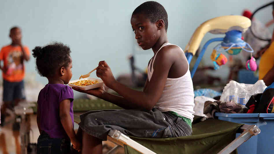 Darrell Hill, 11, feeds his sister Floy Dillon, 2, at a flood shelter in a school gym in Kentwood, La., Thursday. Residents fled to the shelter after officials announced that a dam upstream in Mississippi was in danger of bursting.
