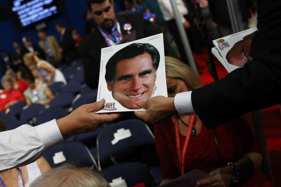 A mask of Mitt Romney is passed out to the crowd.