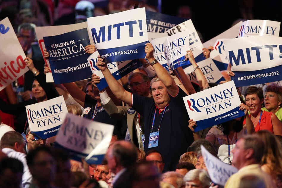 Mitt Romney supporters wave campaign signs.
