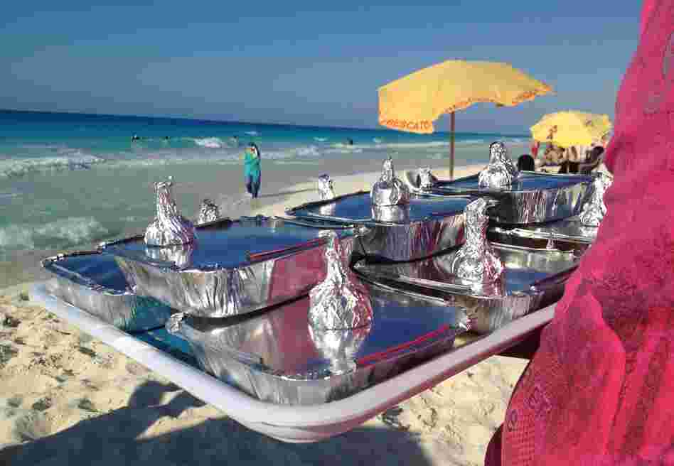 Vendor Amr Abd Elaal balances a tray of gandoufly steamed clams and foil-wrapped half lemons.