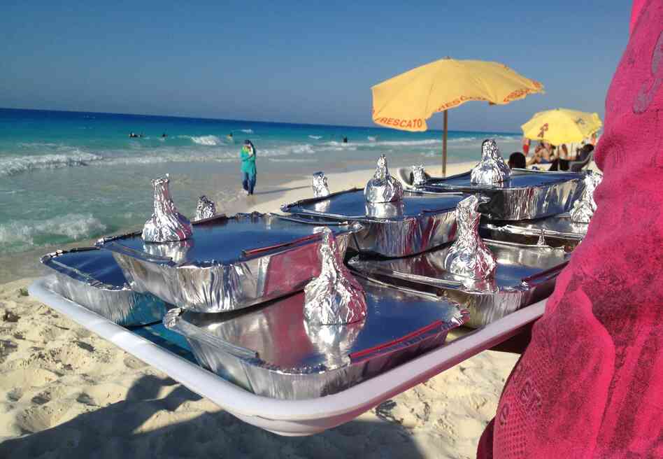 Vendor Amr Abd Elaal balances a tray of gandoufly steamed clams and foil-wrapped half lemons.