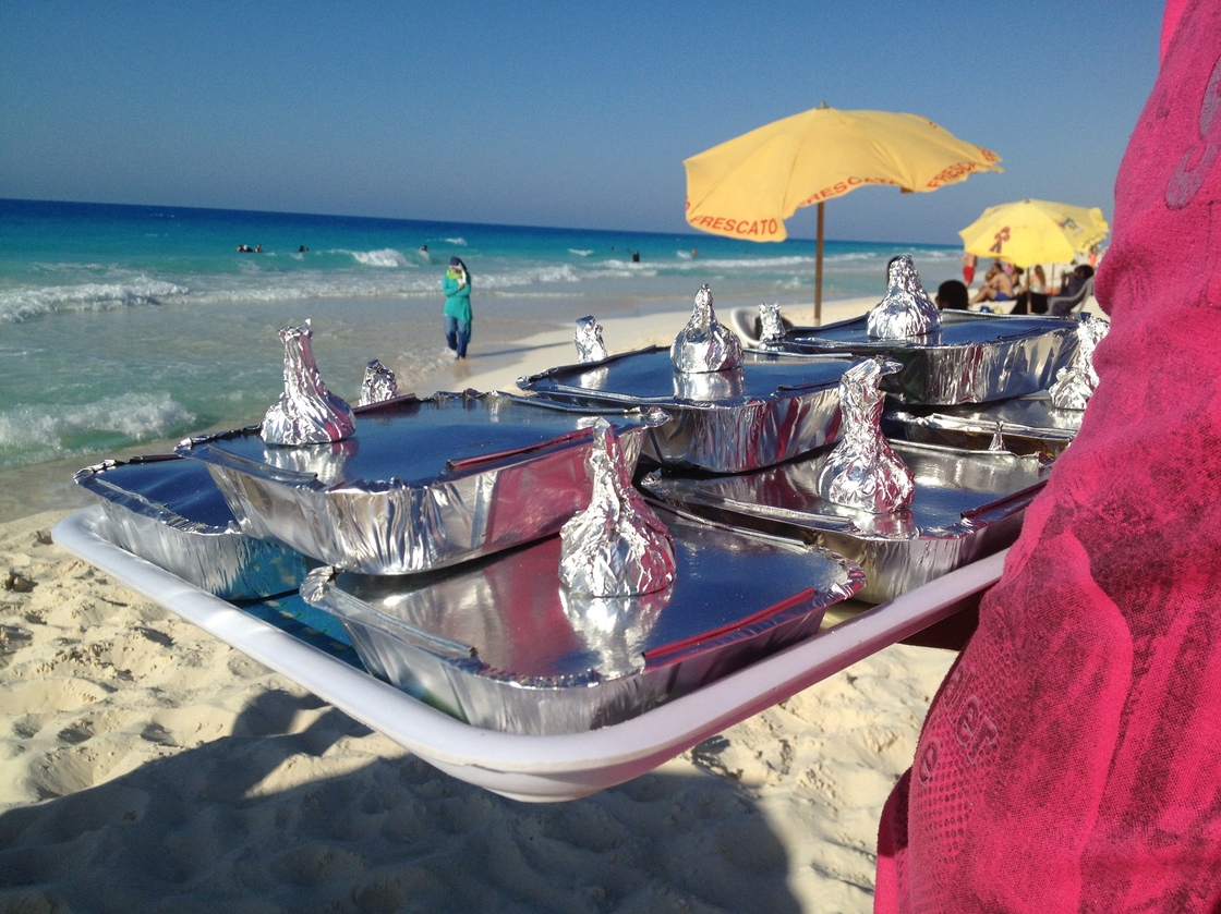 Vendor Amr Abd Elaal balances a tray of gandoufly steamed clams and foil-wrapped half lemons.