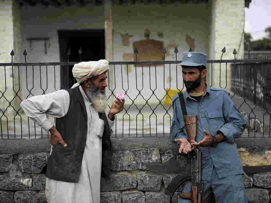 Afghan security forces are already playing a more prominent role, though questions remain about the quality of the forces. Here, an Afghan policeman talks with an elderly man in the eastern province of Khost in August.