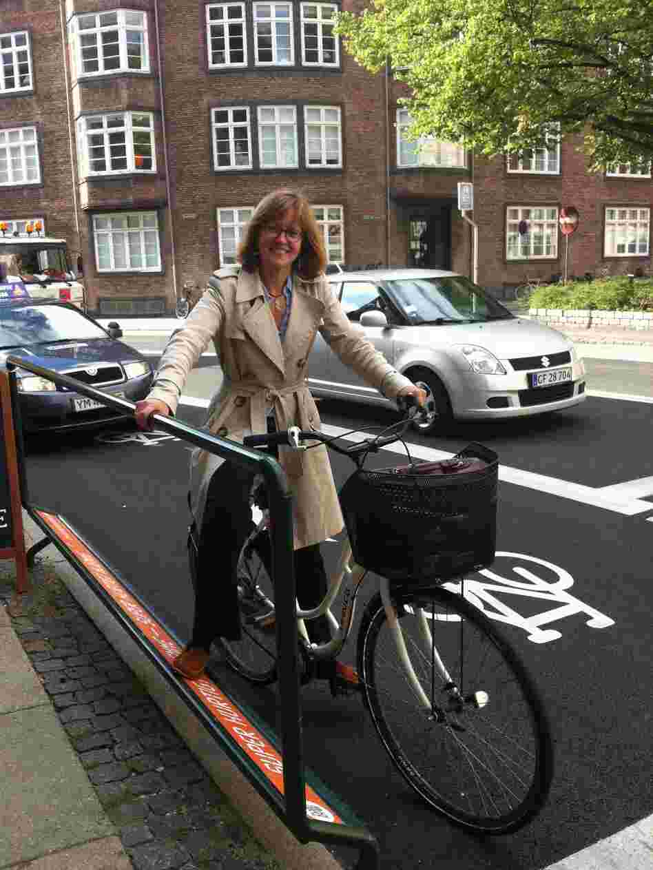 NPR reporter Eleanor Beardsley rides in one of the new bike lanes in Copenhagen. The city is building more than two dozen lanes from the suburbs into the city. They cater to cyclists by including such things as rails and footrests at stoplights.