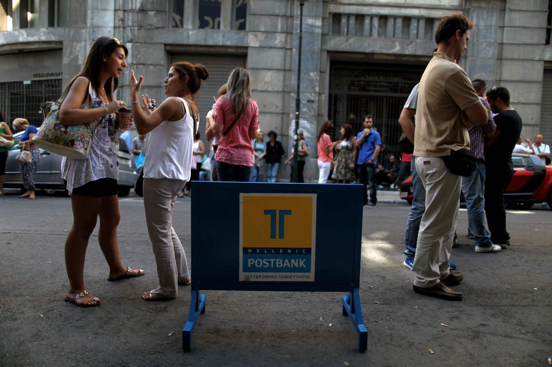 Striking Hellenic Postbank workers chat outside the state-owned bank's headquarters in Athens on Thursday. The union is protesting the government's plan to sell its majority share in the lender.