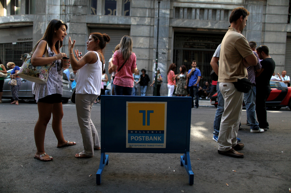 Striking Hellenic Postbank workers chat outside the state-owned bank's headquarters in Athens on Thursday. The union is protesting the government's plan to sell its majority share in the lender.