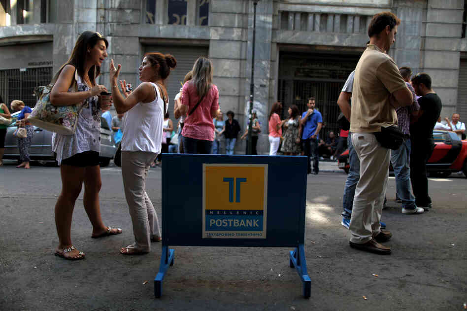 Striking Hellenic Postbank workers chat outside the state-owned bank's headquarters in Athens on Thursday. The union is protesting the government's plan to sell its majority share in the lender.
