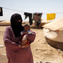 Omm Ahmed, a refugee from Daraa, Syria, carries her infant near her tent at Zaatari Refugee Camp in Mafraq, Jordan, on Sunday. Syrian civilians have borne the greatest brunt of the conflict in their country.