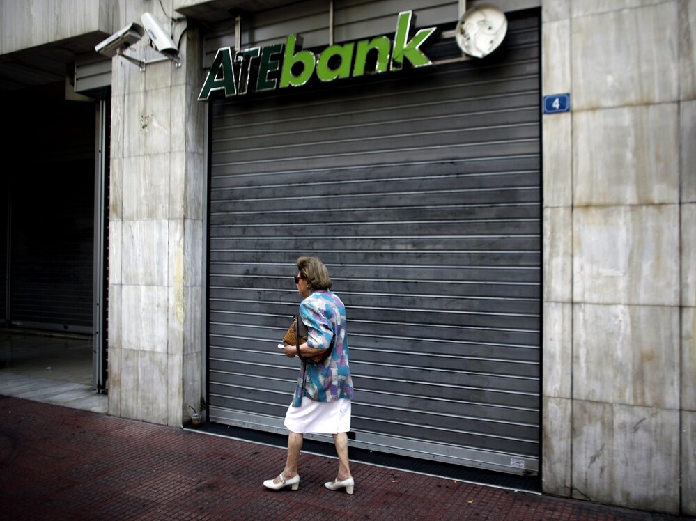 A woman walks past a closed branch of the ATE bank in Athens, on July 30 as employees of the bank went on strike.