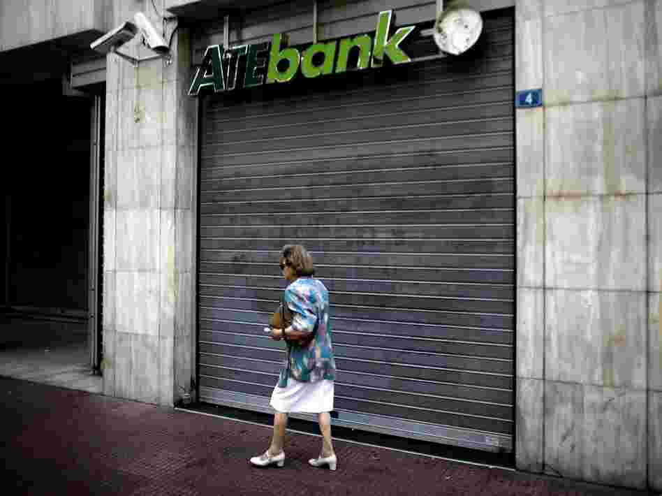 A woman walks past a closed branch of the ATE bank in Athens, on July 30 as employees of the bank went on strike.