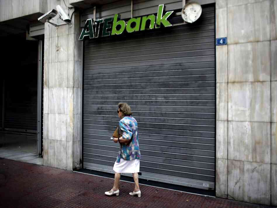 A woman walks past a closed branch of the ATE bank in Athens, on July 30 as employees of the bank went on strike.