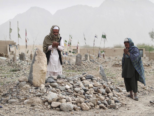 In March, villagers pray over the grave of a victim of a shooting rampage in the Panjwai district of Kandahar province south of Kabul, Afghanistan.
