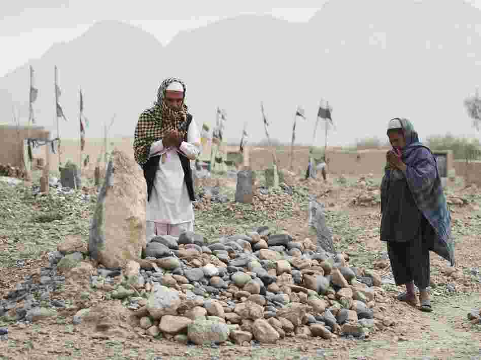 In March, villagers pray over the grave of a victim of a shooting rampage in the Panjwai district of Kandahar province south of Kabul, Afghanistan.