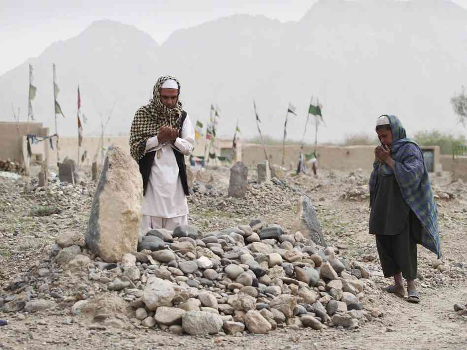In March, villagers pray over the grave of a victim of a shooting rampage in the Panjwai district of Kandahar province south of Kabul, Afghanistan.