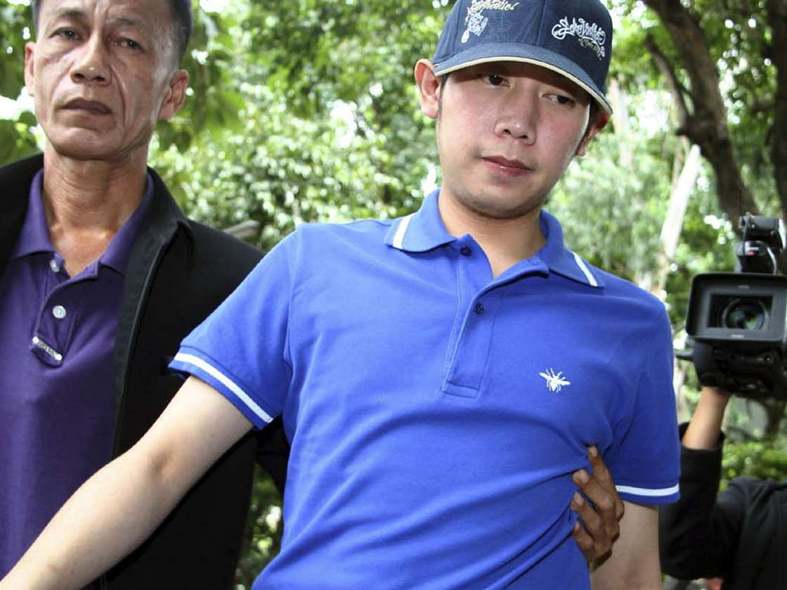Vorayuth Yoovidhya, a grandson of late Red Bull founder Chaleo Yoovidhaya, is taken by a plainclothes police officer for investigation Monday, Sept. 3, 2012 in Bangkok, Thailand. Vorayuth is suspected of driving a Ferrari that struck and killed a policeman and then dragged the officer's body down a Bangkok street.