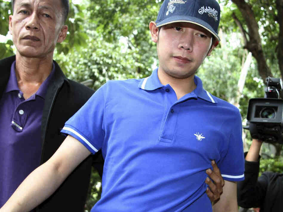 Vorayuth Yoovidhya, a grandson of late Red Bull founder Chaleo Yoovidhaya, is taken by a plainclothes police officer for investigation Monday, Sept. 3, 2012 in Bangkok, Thailand. Vorayuth is suspected of driving a Ferrari that struck and killed a policeman and then dragged the officer's body down a Bangkok street.