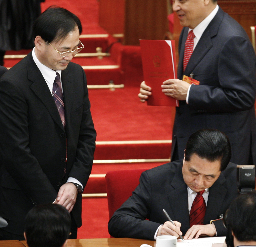 Ling Jihua, left, looked on in March 2010 as Chinese President Hu Jintao, signed a document at the closing ceremony of the National People's Congress in Beijing. Ling has been shifted to a lesser position.