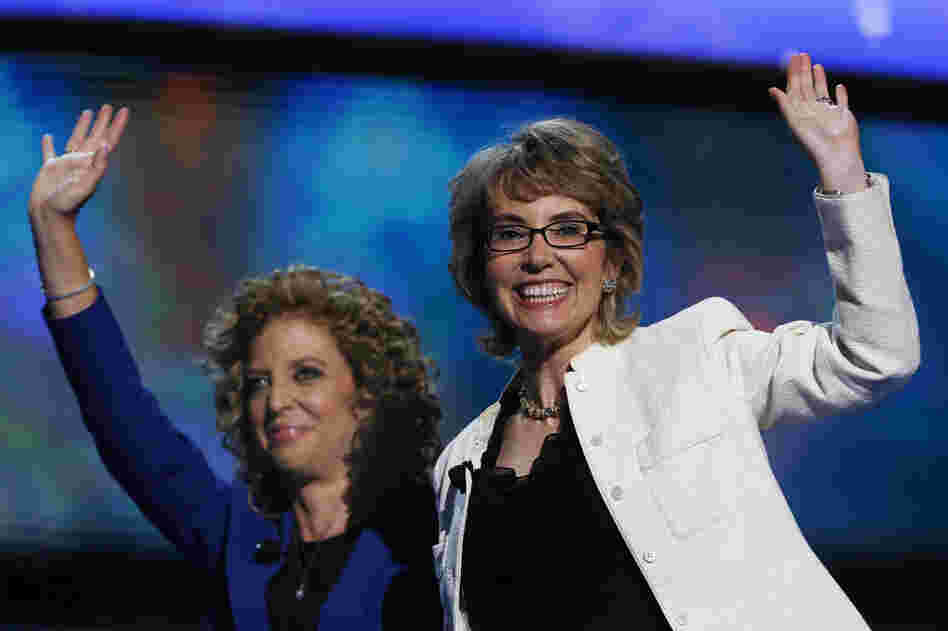 Former Arizona Rep. Gabrielle Giffords (right) and Florida Rep. Debbie Wasserman Schultz wave after reciting the Pledge of Allegiance. Giffords, who was injured in a 2011 shooting rampage, received a standing ovation.