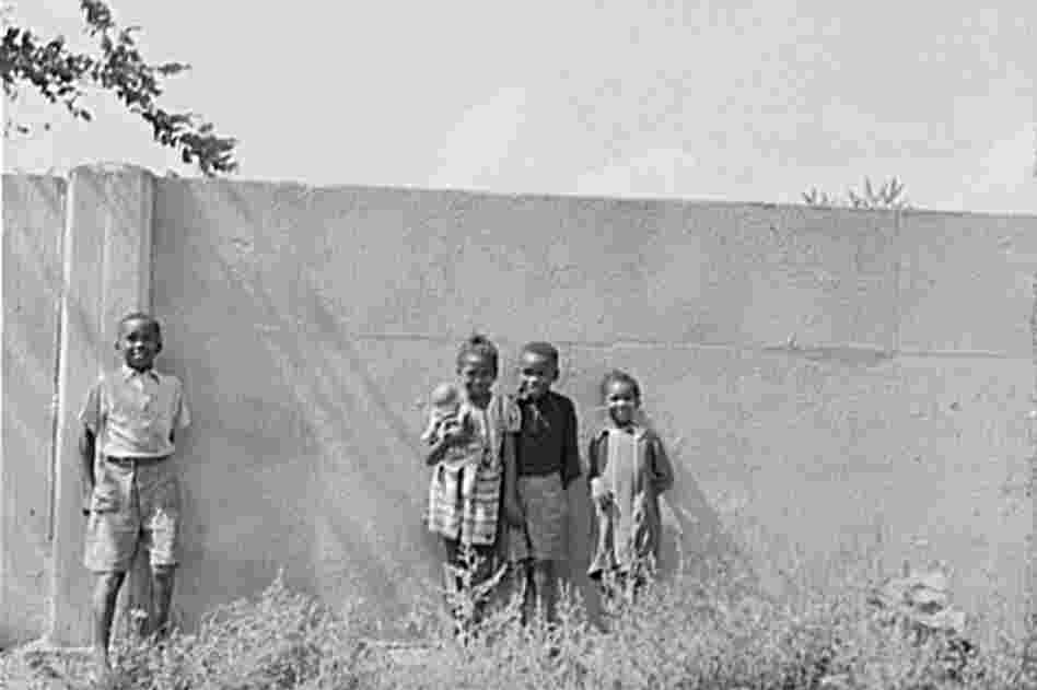 Children stand in front of a half-mile concrete wall in Detroit in 1941. The wall was built in 1940 to separate the black section of the city from a white housing development going up on the other side.