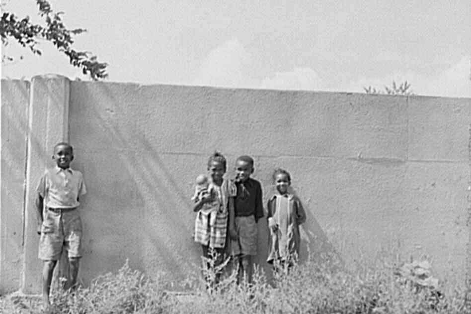 Children stand in front of a half-mile concrete wall in Detroit in 1941. The wall was built in 1940 to separate the black section of the city from a white housing development going up on the other side.