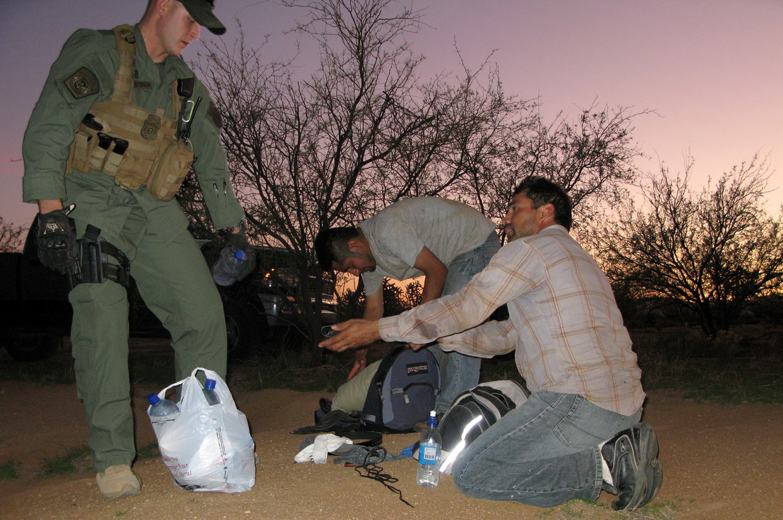 A Border Patrol agent offers water to two men caught after illegally entering the U.S. through the Arizona desert. Roughly 80,000 federal workers have jobs related to immigration enforcement.