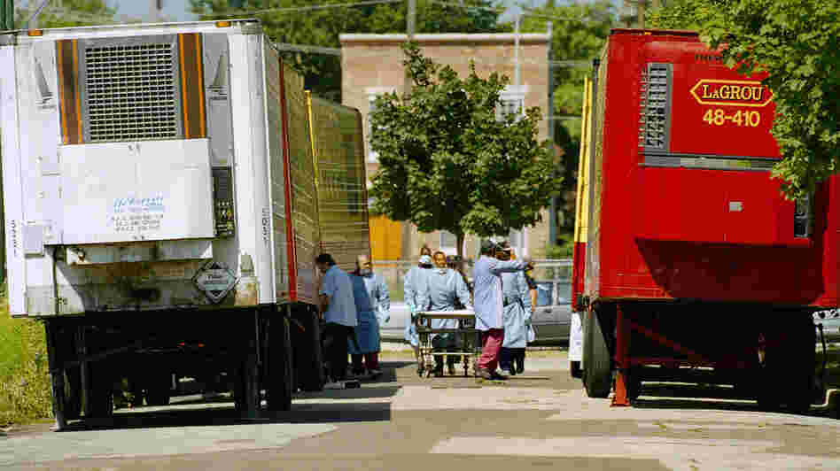 Cook County morgue workers walk between a row of refrigerated trucks outside the morgue in July 1995, when a deadly heat wave struck Chicago.