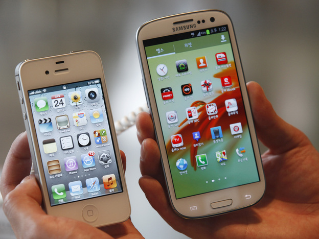 An employee holds Apple's iPhone 4S (left) and Samsung's Galaxy S III at an electronics store in Seoul, South Korea. Some U.S. phone designers are now conflicted over what a recent decision that Samsung infringed on Apple mobile phone patents will mean for their work.