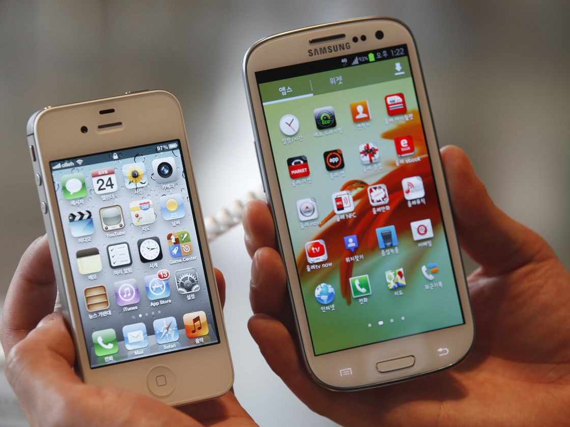 An employee holds Apple's iPhone 4S (left) and Samsung's Galaxy S III at an electronics store in Seoul, South Korea. Some U.S. phone designers are now conflicted over what a recent decision that Samsung infringed on Apple mobile phone patents will mean for their work.