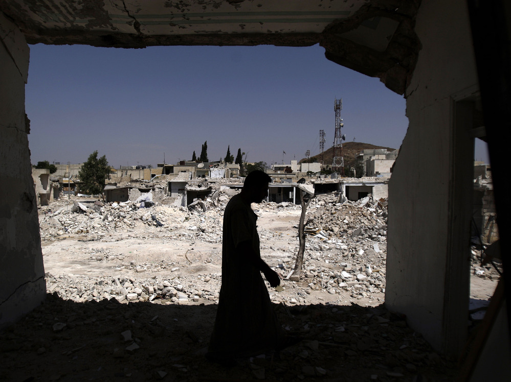 A man walks in his house, which was destroyed in shelling by Syrian government forces, in Azaz, northern Syria. Rebels say the town is under nightly attack.