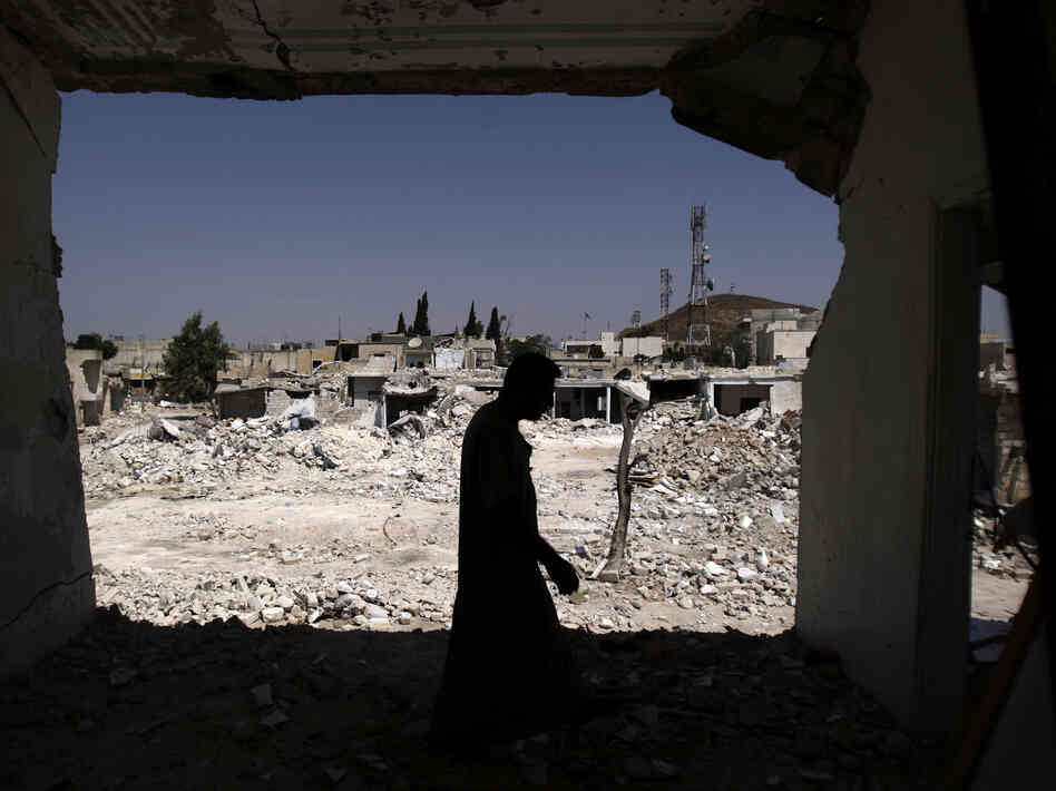 A man walks in his house, which was destroyed in shelling by Syrian government forces, in Azaz, northern Syria. Rebels say the town is under nightly attack.