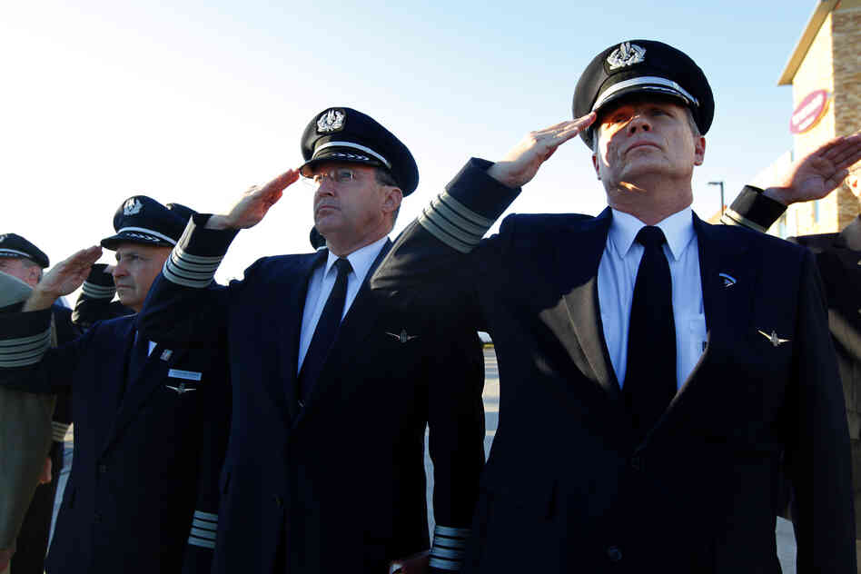 Airline pilots Capt. Anthony Chapman (right) and Capt. Paul Evans salute with others as the U.S. flag is lowered to half staff at the 9/11 Flight Crew Memorial in Grapevine, Texas. Flight crews gathered at the memorial near Dallas-Fort Worth airport to remember the flight crews lost in the Sept. 11 attacks.