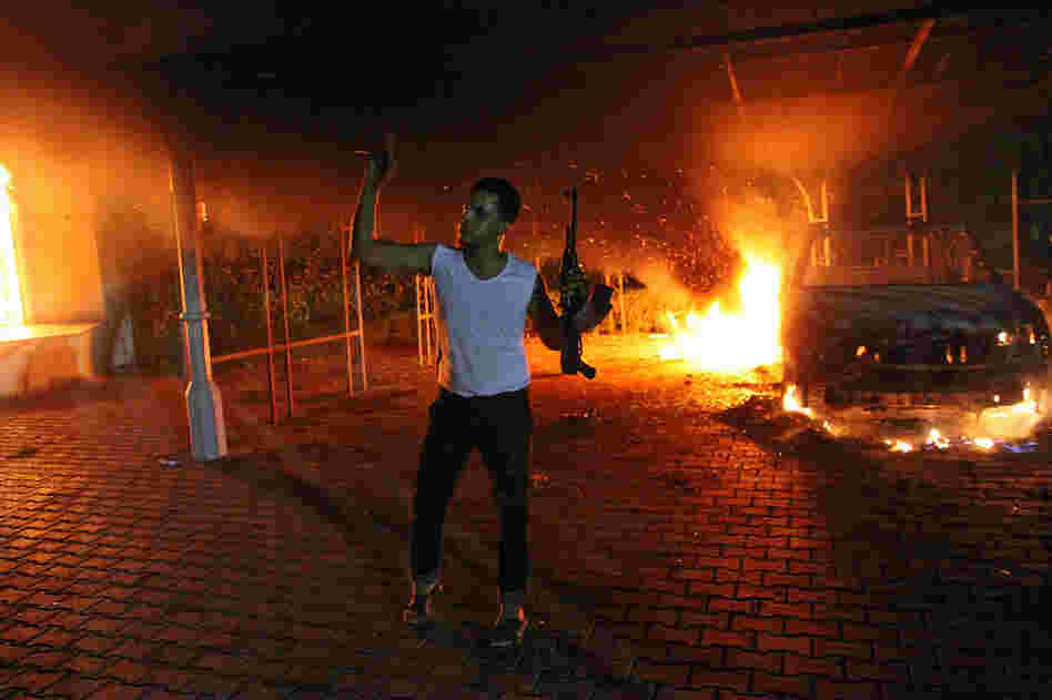 An armed man waves his rifle as buildings and cars are engulfed in flames after being set on fire inside the U.S. Consulate compound in Benghazi late on Tuesday.